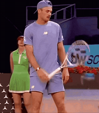 Man Holding Tennis Racquet Woman In Green Dress Behind GIF