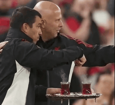 Man Holding Tray Of Tea Hugged By Another GIF