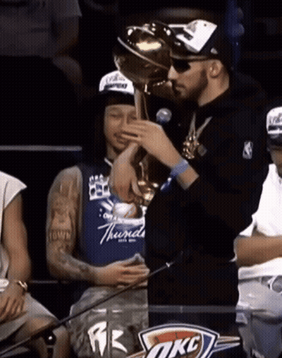 Man Holding Trophy In Front Of OKC Sign GIF