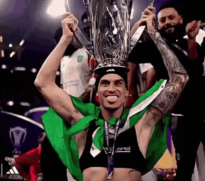 Man Holding Trophy Over Head In Green And White Shirt GIF