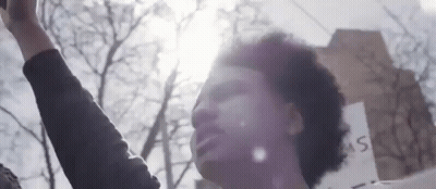 Man Holding Up Fist In Front Of Building GIF