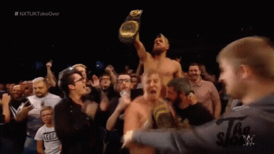 Man Holding Wrestling Championship Surrounded By Fans GIF