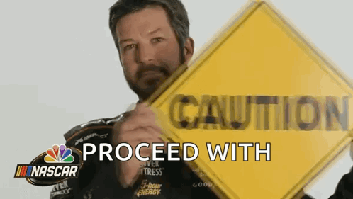 Man Holding Yellow Caution Sign In Front Of NASCAR Logo GIF