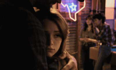 Man Hugging Woman In Front Of Texas Neon Sign GIF