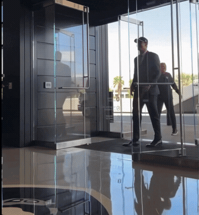 Man In A Suit Walks Through Emergency Exit Glass Door GIF