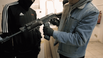 Man In Adidas Jacket Holding Rifle GIF