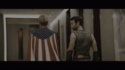 Man In American Flag Cape Next To Superhero GIF