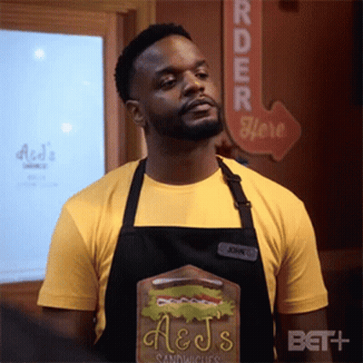 Man In Apron And Yellow Shirt With Sandwich Board GIF