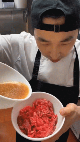 Man In Apron Holding Bowl Of Meat And Bowl Of Sauce GIF