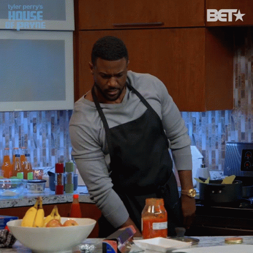 Man In Apron Preparing Food With BET Logo In Background GIF