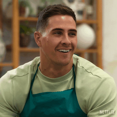 Man In Apron Smiling In Front Of Netflix Shelf GIF