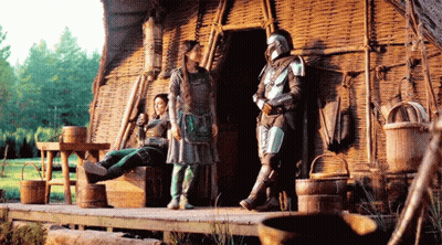 Man In Armor Standing Next To Woman On Bench GIF