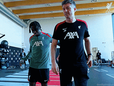 Man In Aya Shirt Walking Next To Man In Green Shirt GIF