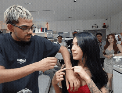 Man In Balenciaga Shirt Adjusting Woman's Wrist GIF