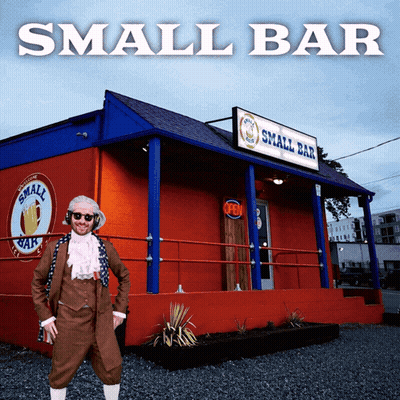 Man In Bar Costume In Front Of Red Building GIF