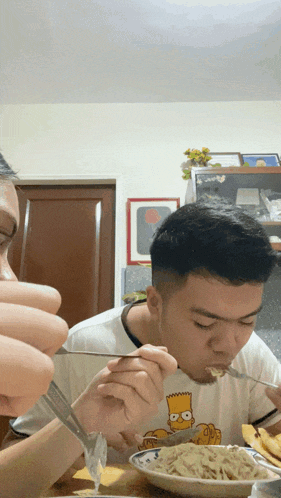 Man In Bart Simpson Shirt Eating Spaghetti With Fork GIF