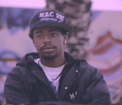 Man In Baseball Cap And Jacket Standing In Front Of Wall GIF