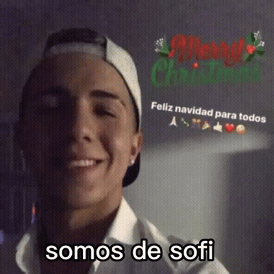 Man In Baseball Cap And White Shirt Smiling At Merry Christmas Sign GIF