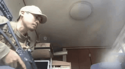 Man In Baseball Cap Holding Gun In Room With Fan GIF