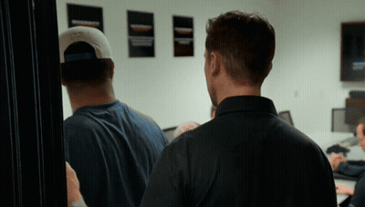 Man In Baseball Cap In Front Of Wall With Posters GIF