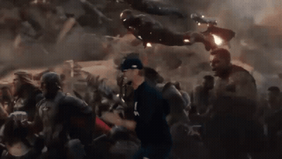 Man In Baseball Cap Running Through Crowd While Iron Man Flies Overhead GIF