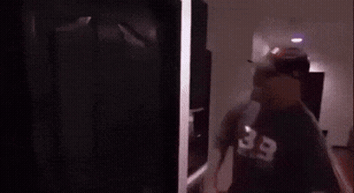 Man In Baseball Cap Standing In Front Of Door GIF