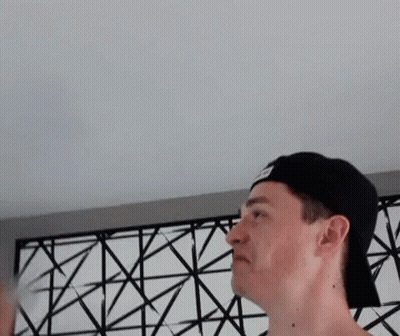 Man In Baseball Cap Standing In Front Of Patterned Wall GIF