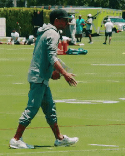 Man In Baseball Cap Walking On Football Field GIF