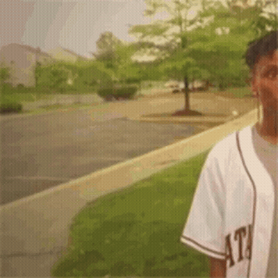 Man In Baseball Jersey On Parking Lot Sidewalk GIF