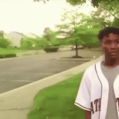 Man In Baseball Uniform On Sidewalk In Park GIF