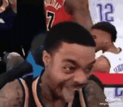 Man In Basketball Uniform Making Funny Face Sitting In Chair GIF