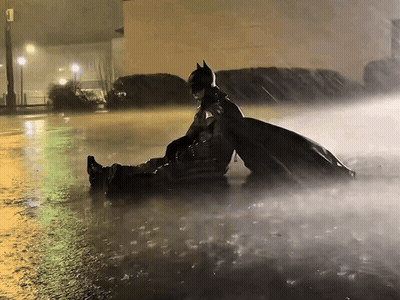 Man In Batman Costume Lying In Rain GIF