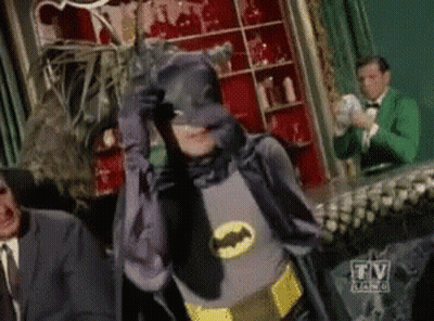 Man In Batman Costume Standing In Front Of TV Sign GIF