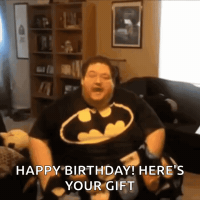 Man in Batman Shirt Holding Game Controller on Couch