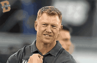 Man In Bcsnn Shirt Smiling At Camera GIF
