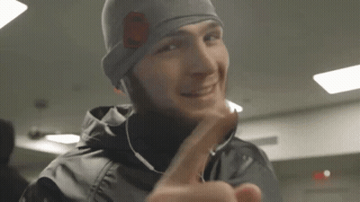 Man In Beanie And Earbuds Smiling Giving Middle Finger GIF
