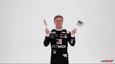 Man In Betmgm Shirt Holding Two American Flags GIF