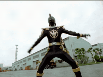 Man In Black And Gold Costume In Front Of White Building GIF