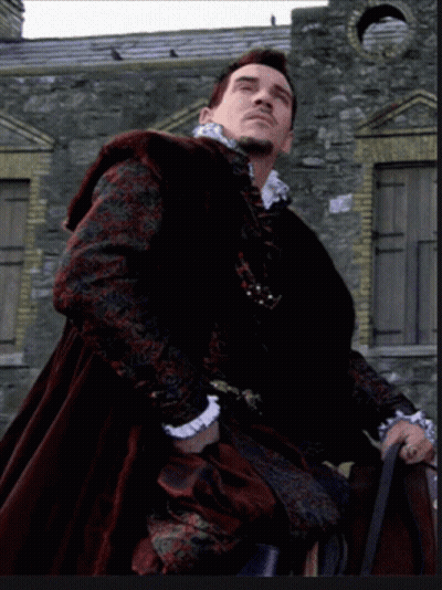 Man In Black And Red Coat In Front Of Stone Wall GIF
