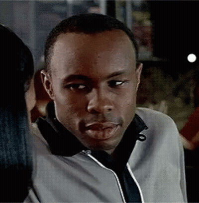 Man In Black And White Jacket In Front Of Mr Roco Sign GIF