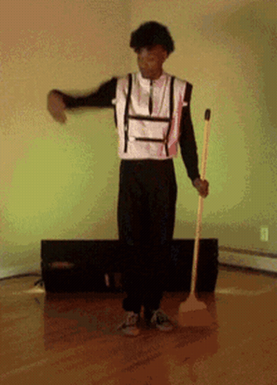 Man In Black And White Outfit Holding Yellow Mop GIF