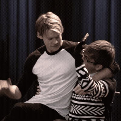 Man In Black And White Sweater Holding Another Man GIF