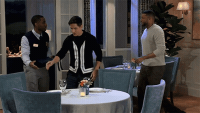 Man In Black And White Sweater Standing In Restaurant GIF