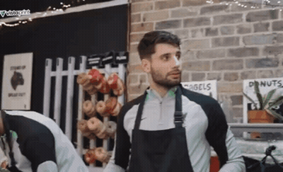 Man In Black Apron Standing In Front Of Brick Wall GIF