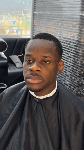 Man In Black Cape Sitting In Barber Chair GIF
