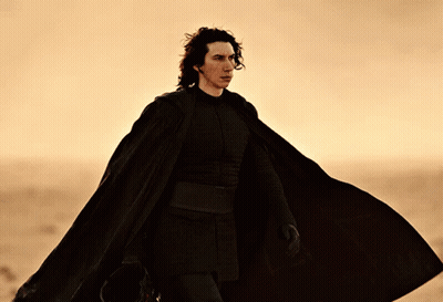 Man In Black Cape Walking Across Desert GIF