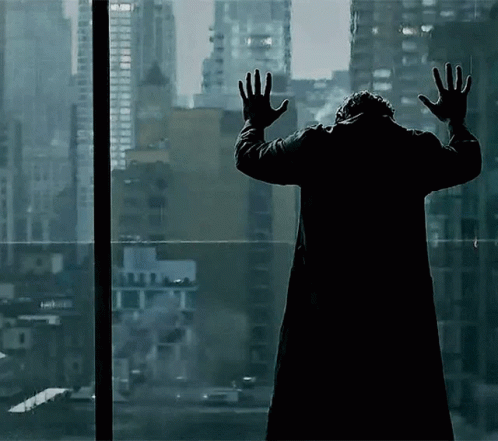 Man In Black Coat Hands Up At Window GIF