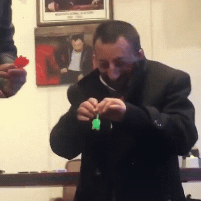 Man In Black Coat Holding Green Toy GIF