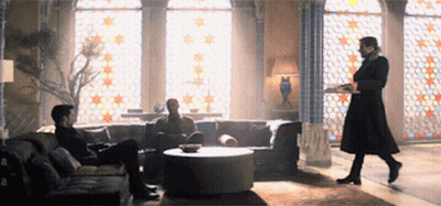Man In Black Coat Holding Tray In Living Room GIF