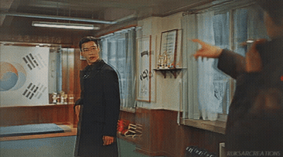 Man In Black Coat Pointing At Flag On Wall GIF
